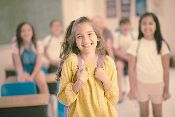 a girl in a yellow top in a classroom smiling