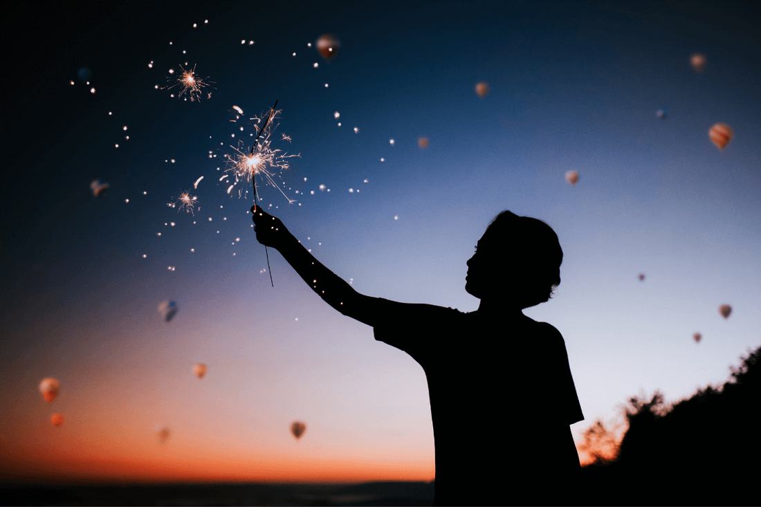 young boy holding a sparkler signifying they have found their spark.  set against a night sky.