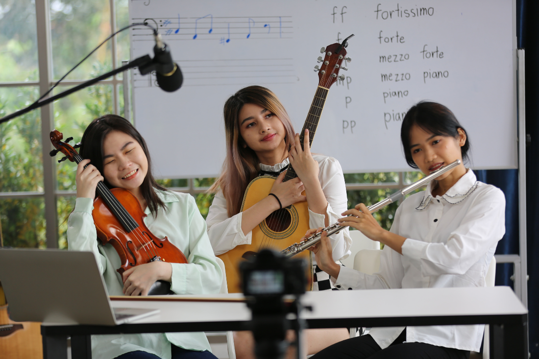three female students, each playing a different musical instrument