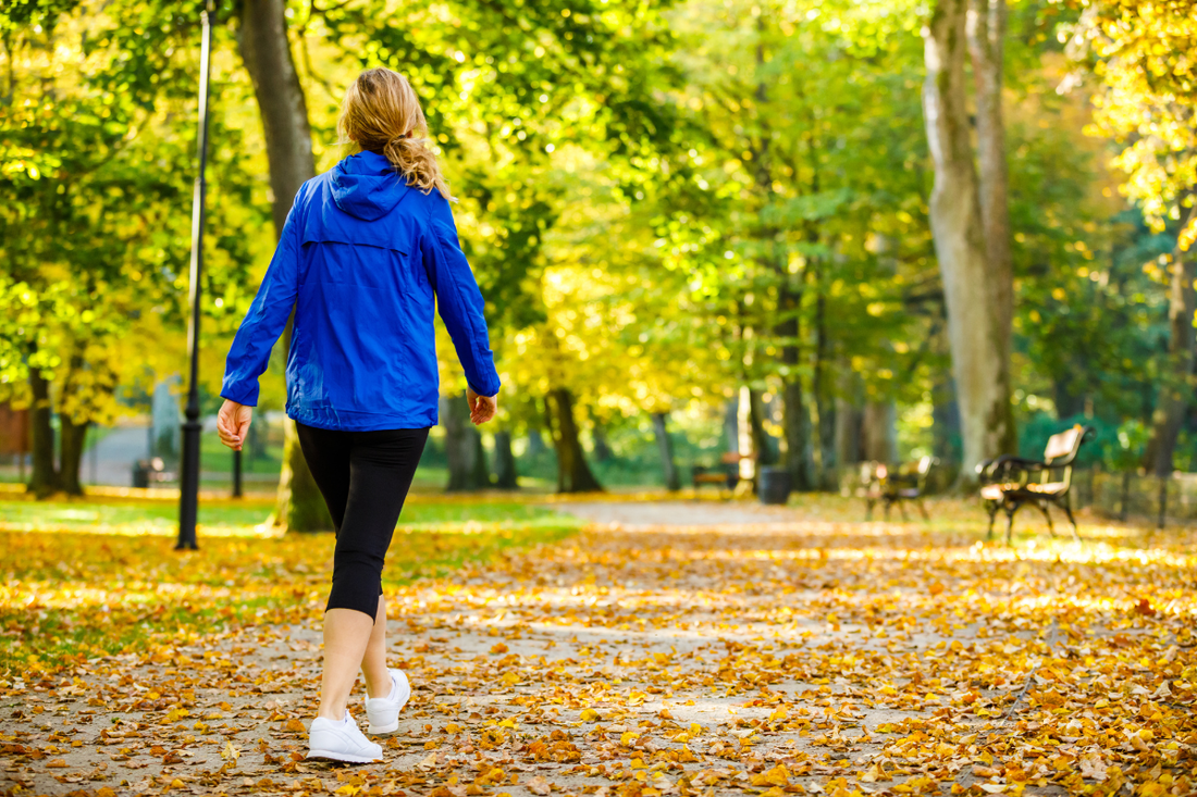 woman wearing a blue raincoat on an autumn path in the park